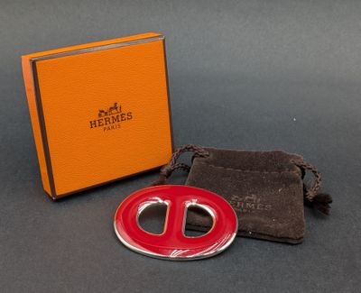 une photo d'une broche rouge et argentée accompagnée d'un sac noir