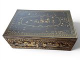 an old black and gold box sitting on top of a white surface