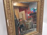une image représentant un miroir à cadre doré posé sur un chevalet en bois