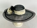 black and white hat with feathers and a bow on top of a hat stand