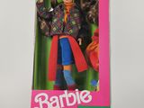 une poupée Barbie dans une boîte, posée sur une surface blanche avec un fond rose