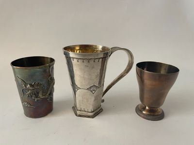two silver cups and a silver cup on a white surface
