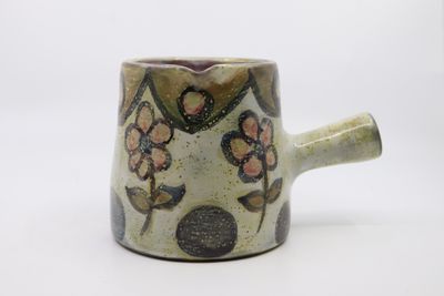 un gros plan d'une tasse avec une anse posée sur une surface blanche