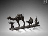 figurine en bronze représentant un chameau et trois hommes, posée sur un socle en bois