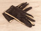 des gants en cuir marron posés sur une table en bois, sur fond blanc