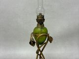 une lampe à huile à l'ancienne, avec un globe en verre vert, posée sur un pied