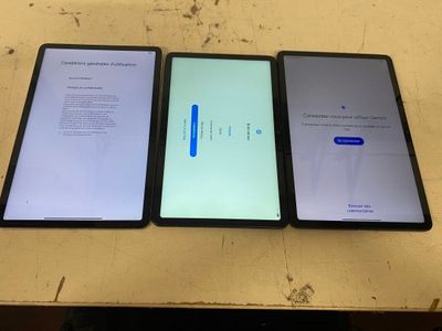 three ipads sitting side by side on a table with one being turned on