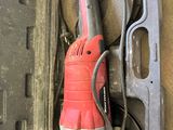 a red corded drill in a case on the floor