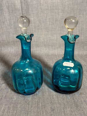 une paire de bouteilles en verre bleues avec des bouchons transparents, sur fond gris