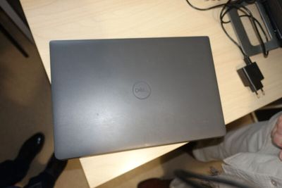someone is holding a dell laptop on a desk with a charger on it
