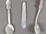 three spoons and two spoons sitting on a table