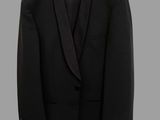 black tuxedo suit hanging on a hanger on a gray background