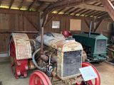 un vieux tracteur garé dans une grange au toit en bois