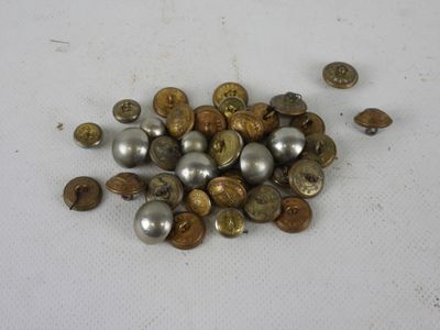 a pile of silver and gold buttons on a white surface