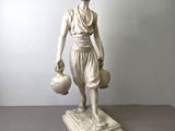statue d'une femme tenant une cruche d'eau, posée sur un socle