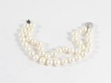un gros plan sur un collier de perles blanches muni d'un fermoir en diamant