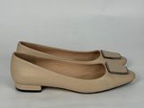 un gros plan sur une paire de chaussures beiges posées sur une surface blanche