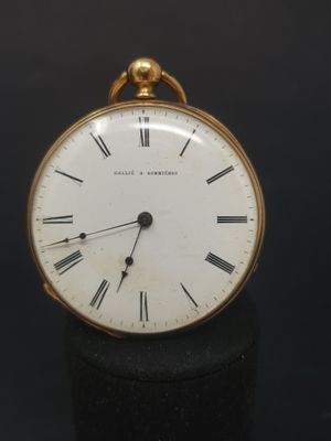 a small gold pocket watch with roman numerals on it