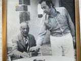 framed photograph of two men sitting at a table with a plate of food in front of them
