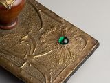a gold book with a green stone on top of it