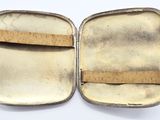a small silver case with a wooden handle on a white surface