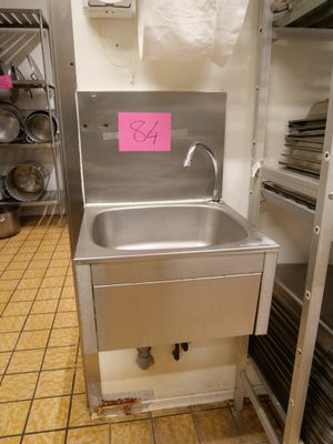 un évier dans une cuisine où il y a beaucoup de casseroles et de poêles