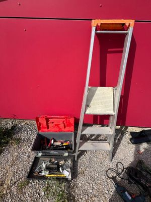 a ladder and a tool box next to a red wall