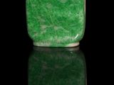 green jade snuff bottle with a red cap on a black surface