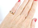 a woman ' s hand with a red manicure and a gold ring on it