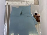 emballage d'un lit avec une couette bleue et deux oreillers
