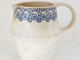 a blue and white pitcher sitting on a white table