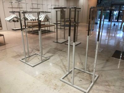 trois portants métalliques sur lesquels sont suspendus des vêtements, dans une pièce