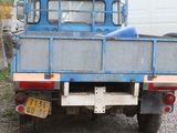 a blue truck that is parked in the gravel