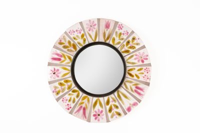 un miroir rond orné d'un motif rose et jaune