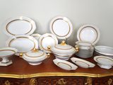 une multitude d'assiettes et de bols blancs et dorés posés sur une table