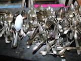 un tas de couverts posé sur une table, à côté d'autres couverts