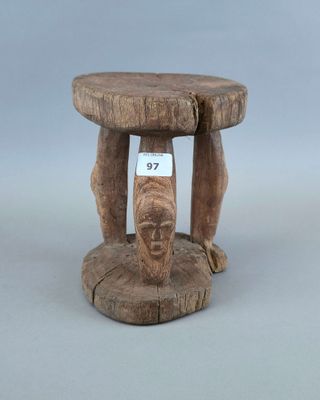 un vieux tabouret en bois sur lequel est posée une pancarte