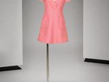 une robe rose posée sur un mannequin devant un fond gris