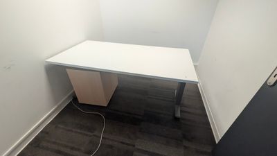 an empty desk in a corner of a room next to a wall