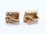 pair of gold tone earrings with swirl design on them on a white surface