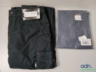Deux paires de jeans noirs sont posées sur une table, à côté d'un sac en plastique.