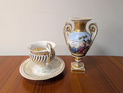 une tasse et une soucoupe posées sur une table, à côté d'un vase