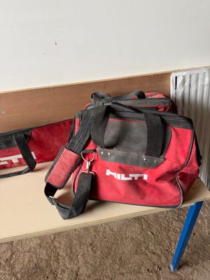 a red duffel bag sitting on a table next to a radiator
