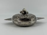 un plat en argent avec un couvercle orné d'un oiseau