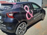 a black car with a pink ribbon on it parked in front of a building