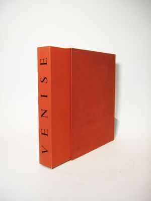 an orange book sitting on top of a white table next to a white wall