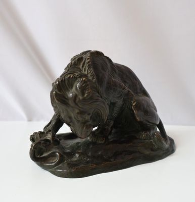 bronze statue of a lion on a rock on a white background