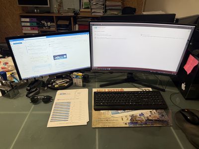 deux écrans d'ordinateur posés sur un bureau, avec un clavier et une souris