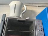 a toaster oven sitting on top of a shelf next to a kettle