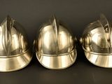three shiny metal helmets sitting on top of a black surface